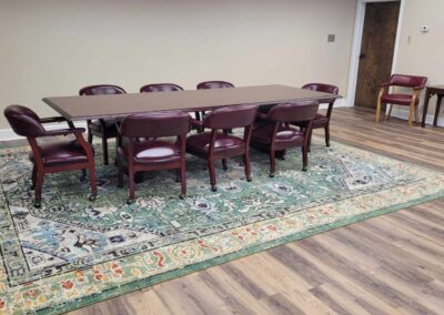 Large wooden conference table surrounded by red leather chairs.