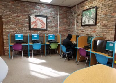 Young person using one of six computers that lining the wall.