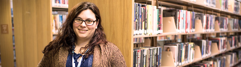 Librarian smiling in front of book shelves at Bolivar County Library System
